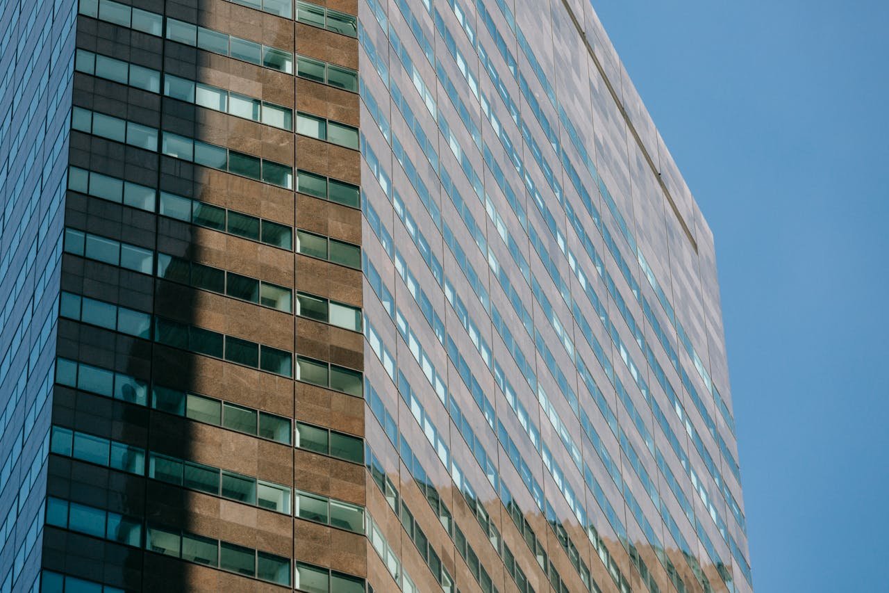 A contemporary skyscraper featuring glass walls with symmetric design against a clear blue sky.